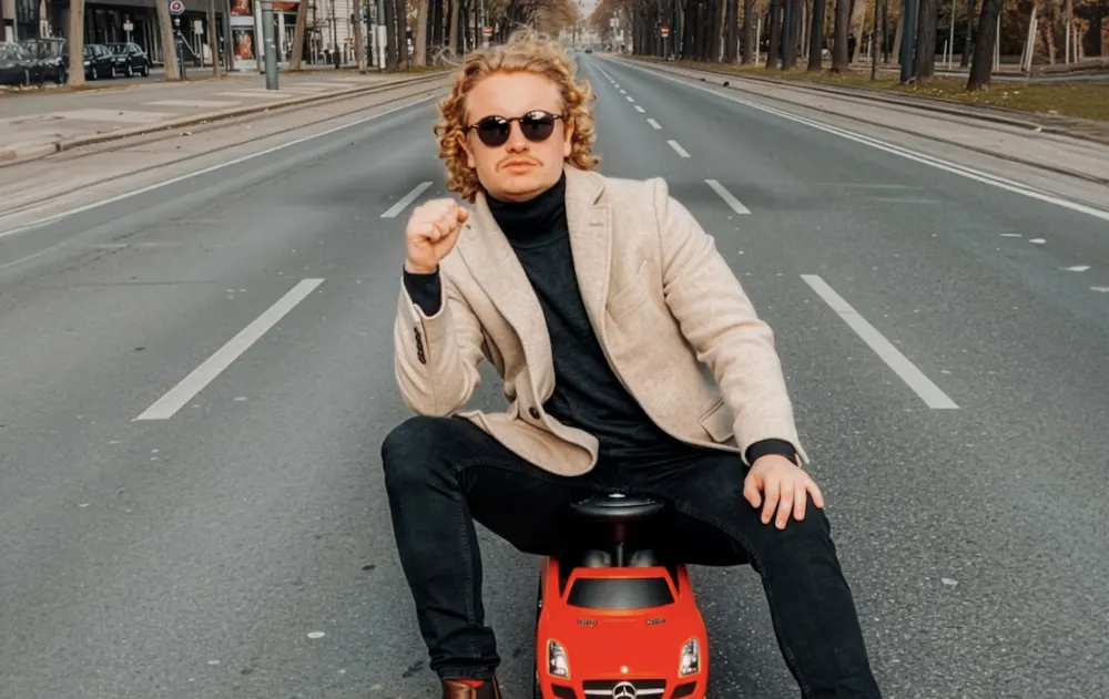 Dr. Bohl auf einem roten Bobby-Car mitten auf einer leeren Straße
