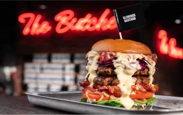 Burger před neonovým nápisem „The Butcher“